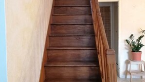 A wooden staircase with a wooden handrail, leading to a room with a potted plant and a small table. - FALE TAHI - Les Petites rives de la Motte (PLEUGUENEUC)