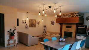 A modern living room with a dining area, a fireplace, and a kitchen. - FALE TAHI - Les Petites rives de la Motte (PLEUGUENEUC)