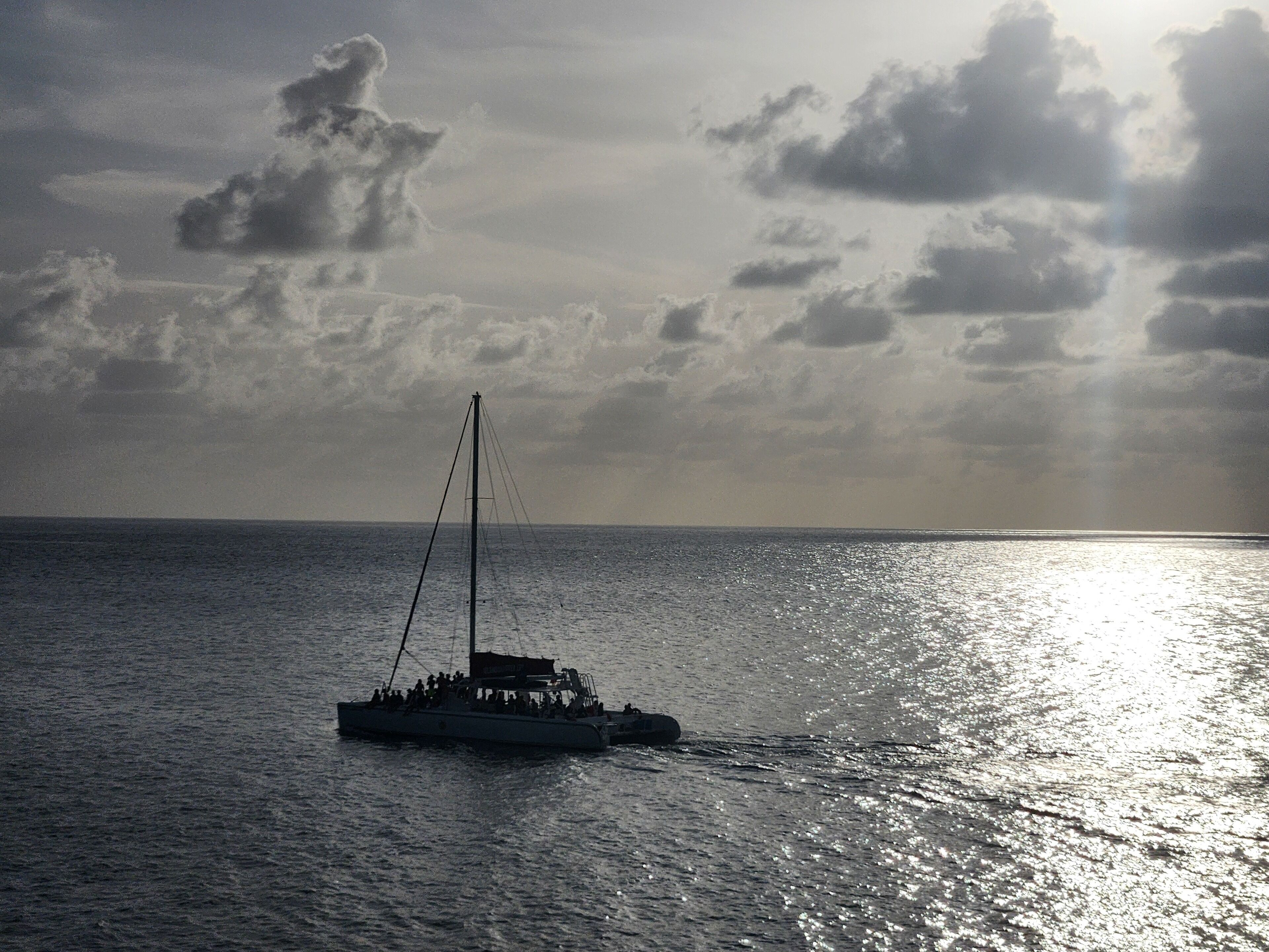 A sailboat on calm waters with a cloudy sky.