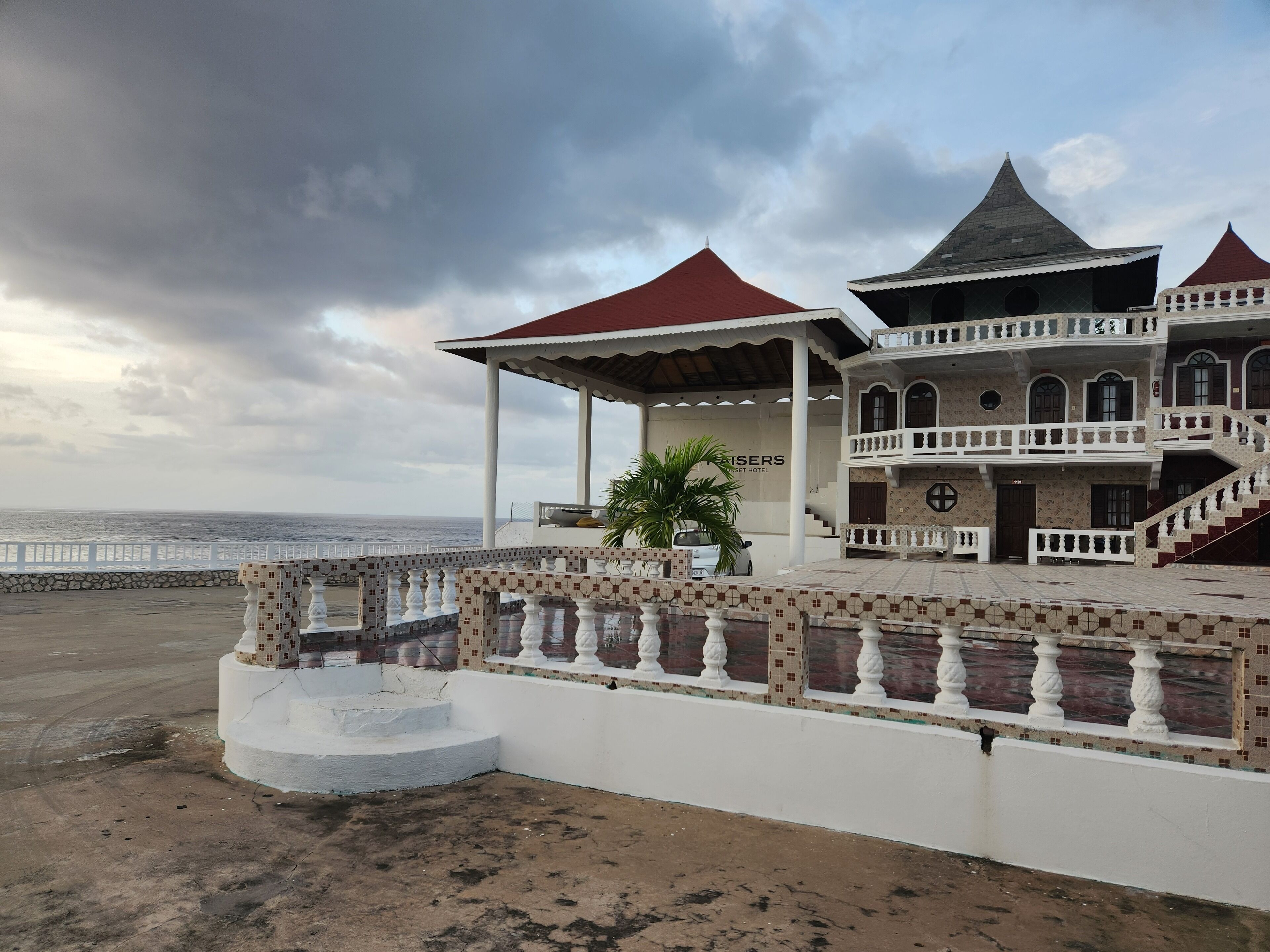 Un hotel con terraza cubierta, piscina y vistas al mar.