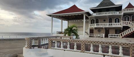 Un hotel con terraza cubierta, piscina y vistas al mar.