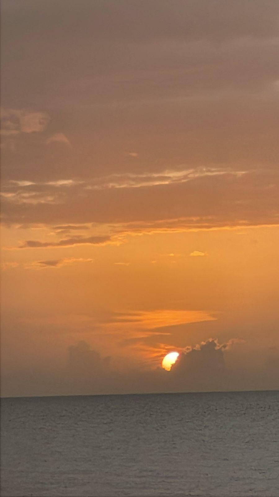 Een zonsondergang boven het water, met een heldere horizon.