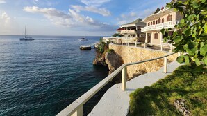 Ein Küstengebäude mit einer Stein-Fassade, einem Balkon und Blick auf das Meer mit Booten.