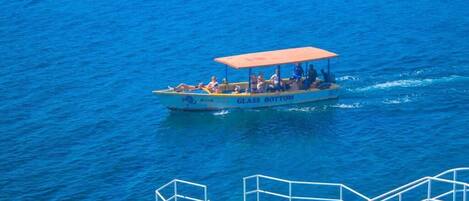 A boat with "GLASS BOTTOM" written on it, moving on the water.