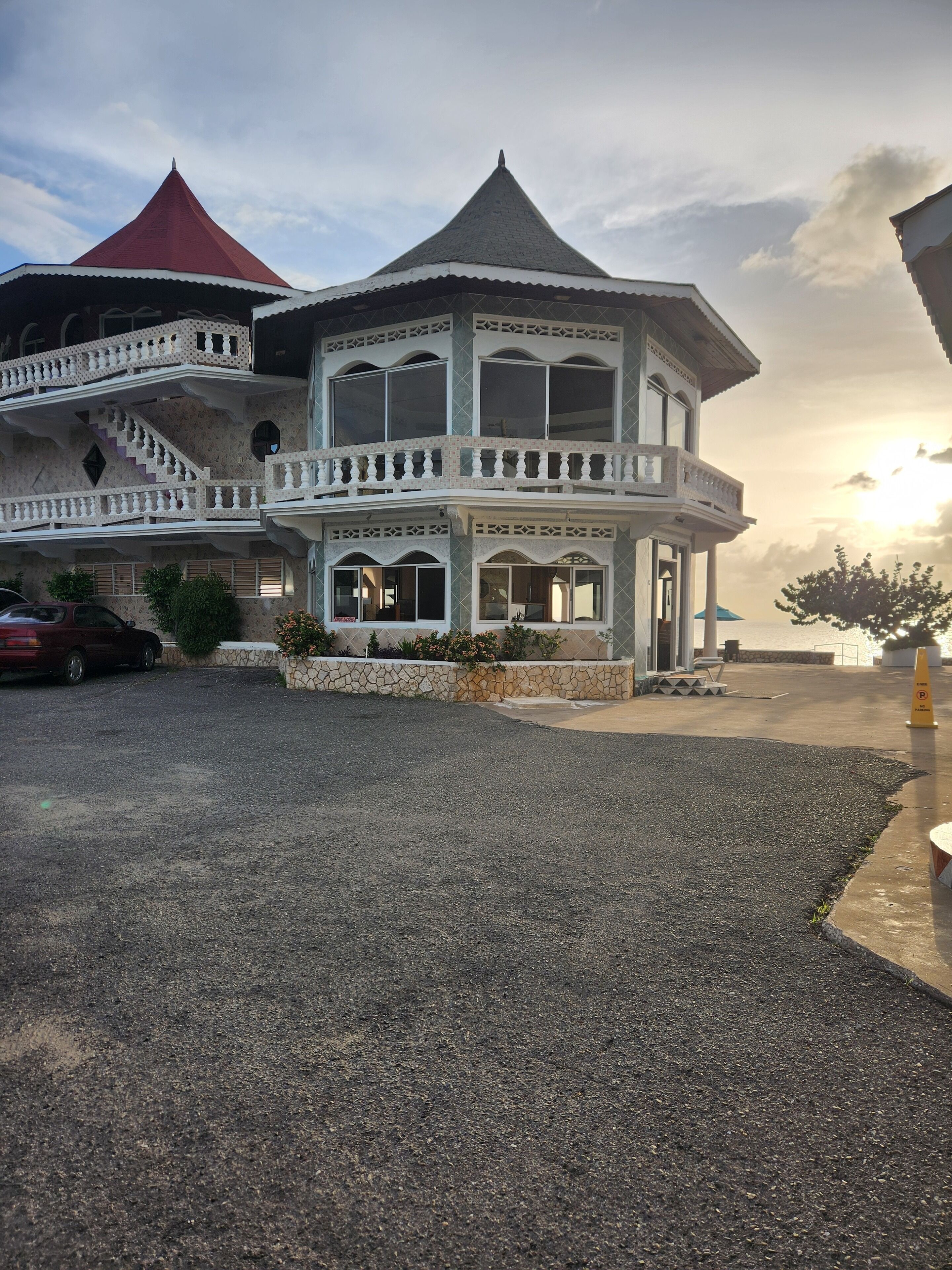 A two-story building with a balcony, a red roof, and a stone facade.