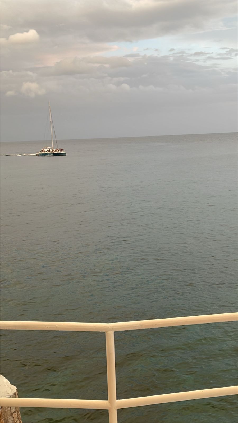 A calm sea with a sailboat in the distance.