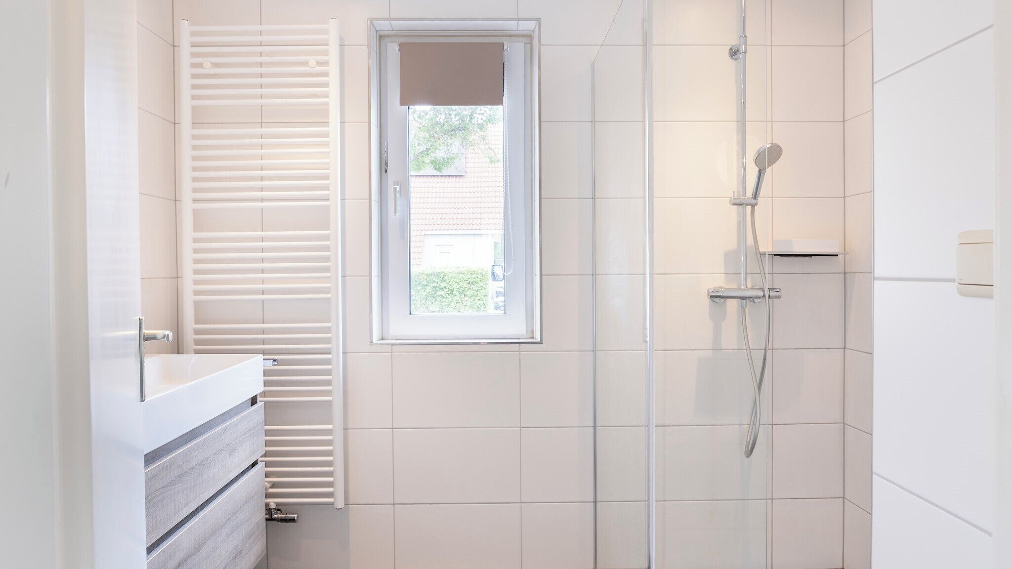 Une salle de bain moderne équipée d’une douche, d’une fenêtre et d’un porte-serviettes.