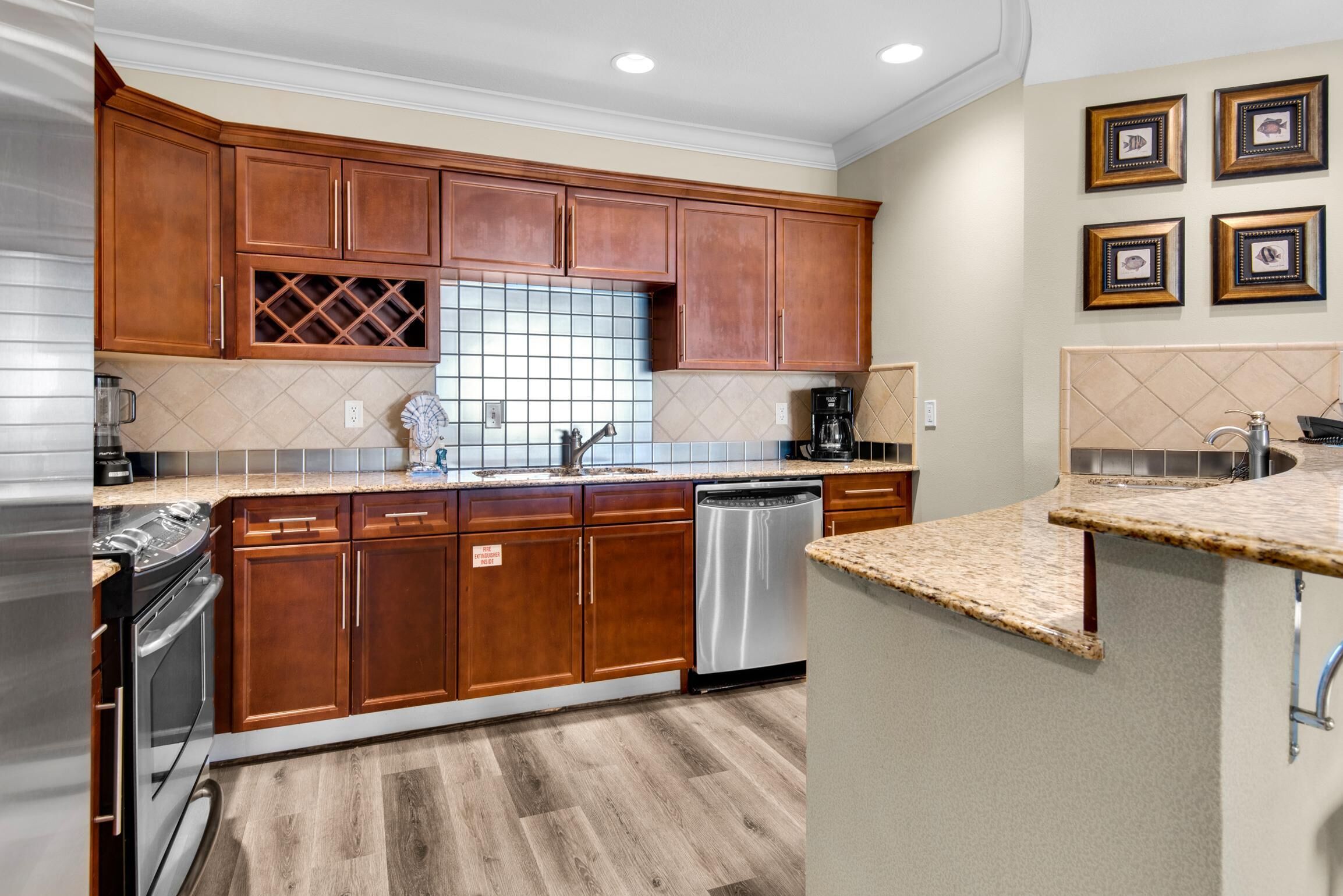 Una cocina con armarios de madera, electrodomésticos de acero inoxidable, salpicadero de azulejos y encimera de granito.