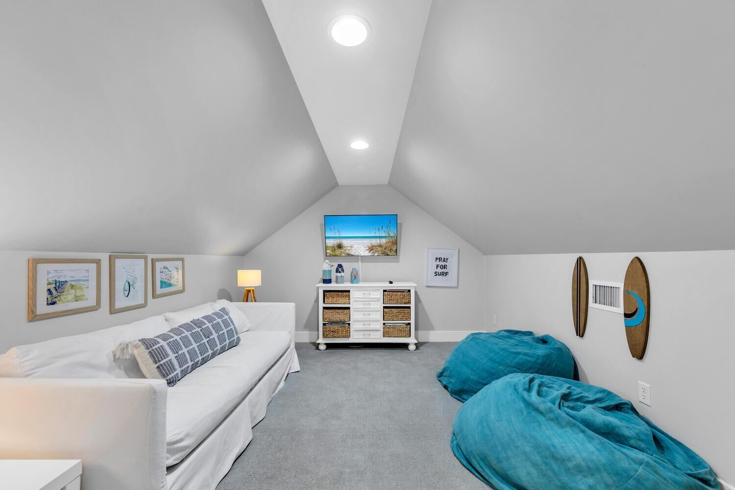 A bedroom with a bed, a dresser, a desk, and a chair. There are wall decorations and a ceiling light.