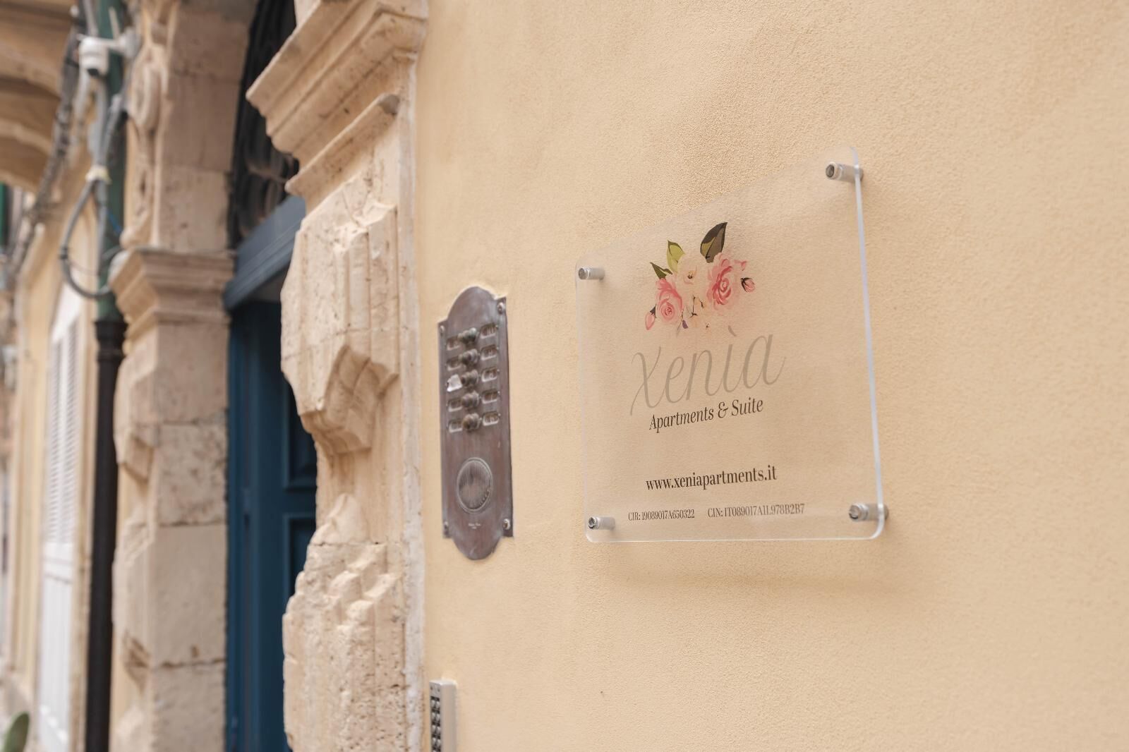 A sign for 'Xenia Apartments & Suite' with a website URL and contact information.