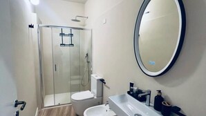 A modern bathroom with a glass shower enclosure, a white sink, and a large mirror.