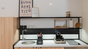 A modern kitchen with a sink, coffee machine, and a framed sign above the counter.