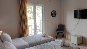 A hotel room with two beds, a TV, a dartboard, and a chair.