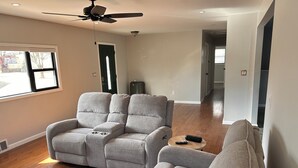 A spacious living room with a grey sectional sofa, a ceiling fan, and a wooden floor. - Newly Renovated 4-Bedroom Saugerties Home 10 minutes from HITS with AC and Wi-Fi (Saugerties)