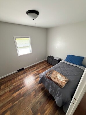 A bedroom with a bed, a nightstand, a dresser, a window, and a ceiling light fixture. - Newly Renovated 4-Bedroom Saugerties Home 10 minutes from HITS with AC and Wi-Fi (Saugerties)