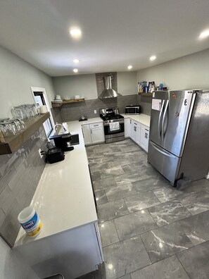 A modern kitchen with a stainless steel refrigerator, a microwave, and a gas stove.