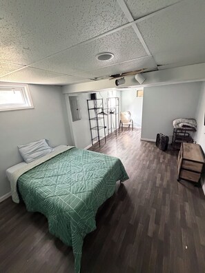 A room with a bed, a chair, a wardrobe, and a shelf unit. - Newly Renovated 4-Bedroom Saugerties Home 10 minutes from HITS with AC and Wi-Fi (Saugerties)