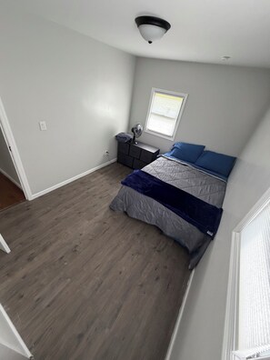 A bedroom with a bed, dresser, and a window.