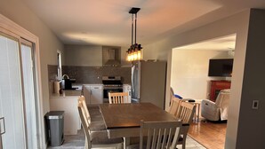 A modern kitchen with a dining area, featuring a large wooden table and chairs, a built-in oven, and a TV in the adjacent living room. - Newly Renovated 4-Bedroom Saugerties Home 10 minutes from HITS with AC and Wi-Fi (Saugerties)
