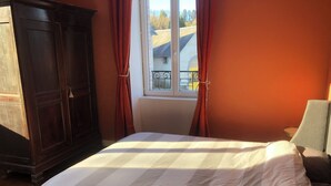 Une chambre à coucher avec un lit, une armoire et une fenêtre avec des rideaux.