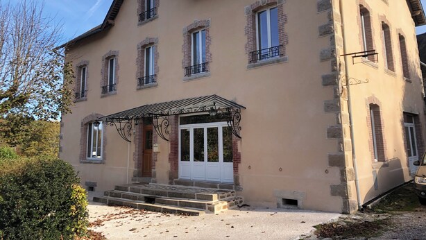 Un bâtiment à deux étages doté d’une façade symétrique, de nombreuses fenêtres et d’une entrée centrale avec des marches menant à une porte.