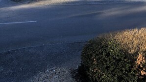 Une rue résidentielle bordée de maisons, avec une voiture garée et un ciel dégagé.
