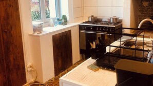 Une cuisine équipée d’une cuisinière à gaz, d’un évier et d’une fenêtre.