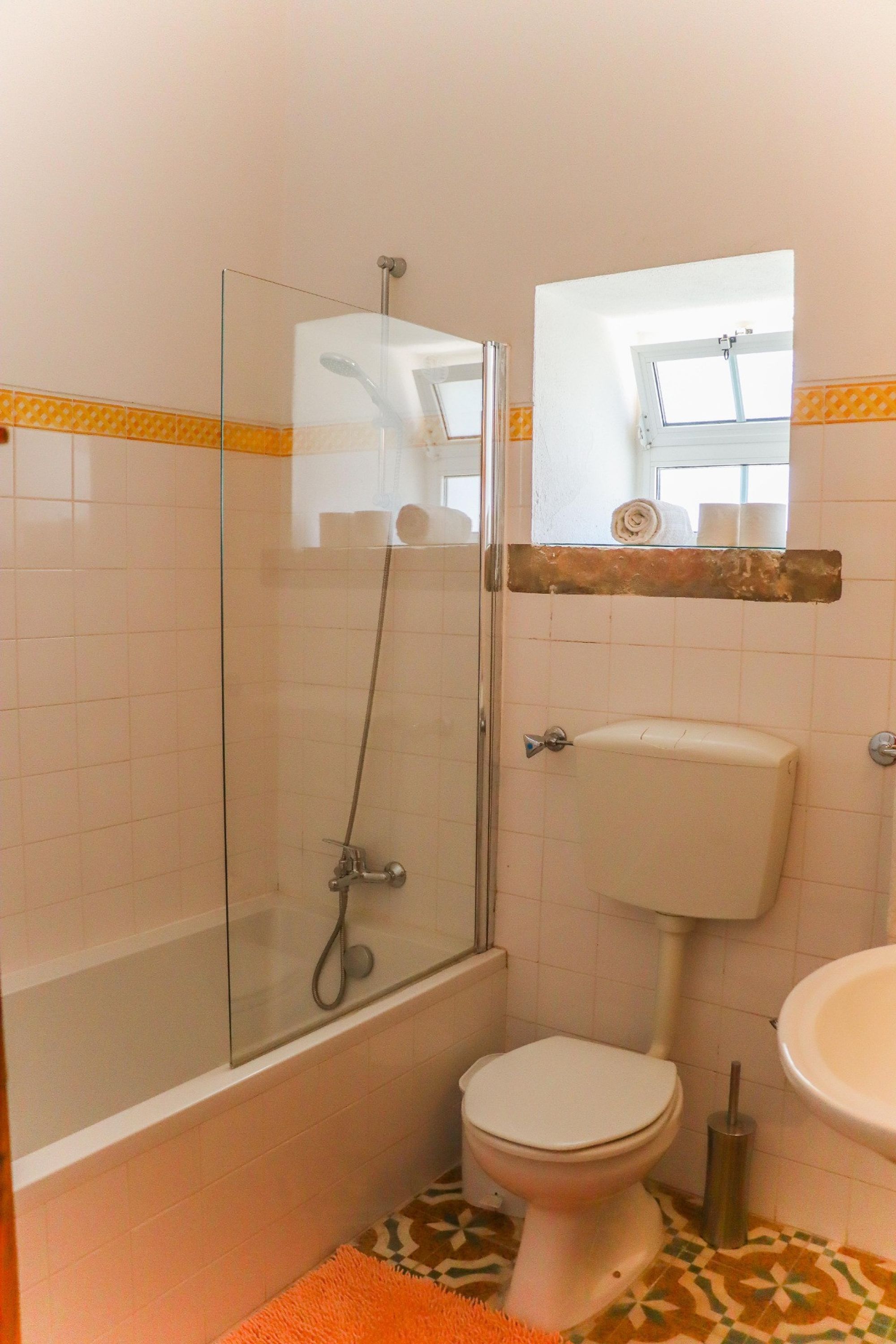 Een badkamer met een douche met glazen wand, toilet en wastafel.