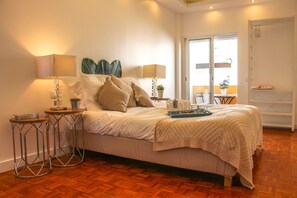 A neatly arranged bedroom with a bed, two bedside tables, a lamp, and a potted plant. - Luxury Flat With Amazing Terrace in Faro (Faro)
