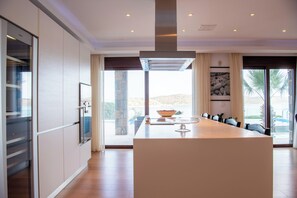 Een moderne keuken met een centraal eiland, grote ramen en uitzicht op het landschap.
