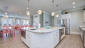 A modern kitchen with white cabinetry, a central island, stainless steel appliances, and pendant lighting. - Beachfront 8bedrooms Lemonshello (Gulf Shores)