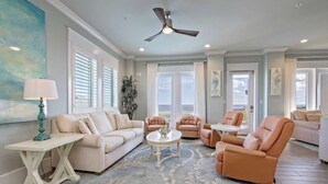 A spacious living room with a beige sofa, two armchairs, a coffee table, and a ceiling fan. - Beachfront 8bedrooms Lemonshello (Gulf Shores)