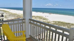 A beach view from a balcony with a yellow chair and a railing. - Beachfront 8bedrooms Lemonshello (Gulf Shores)