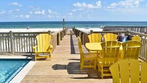 A wooden deck with yellow chairs and tables overlooking a beach. - Beachfront 8bedrooms Lemonshello (Gulf Shores)