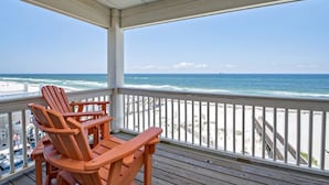A wooden deck with two Adirondack chairs overlooking a beach with a wooden boardwalk. - Beachfront 18bed Pool Easybreezy (Gulf Shores)
