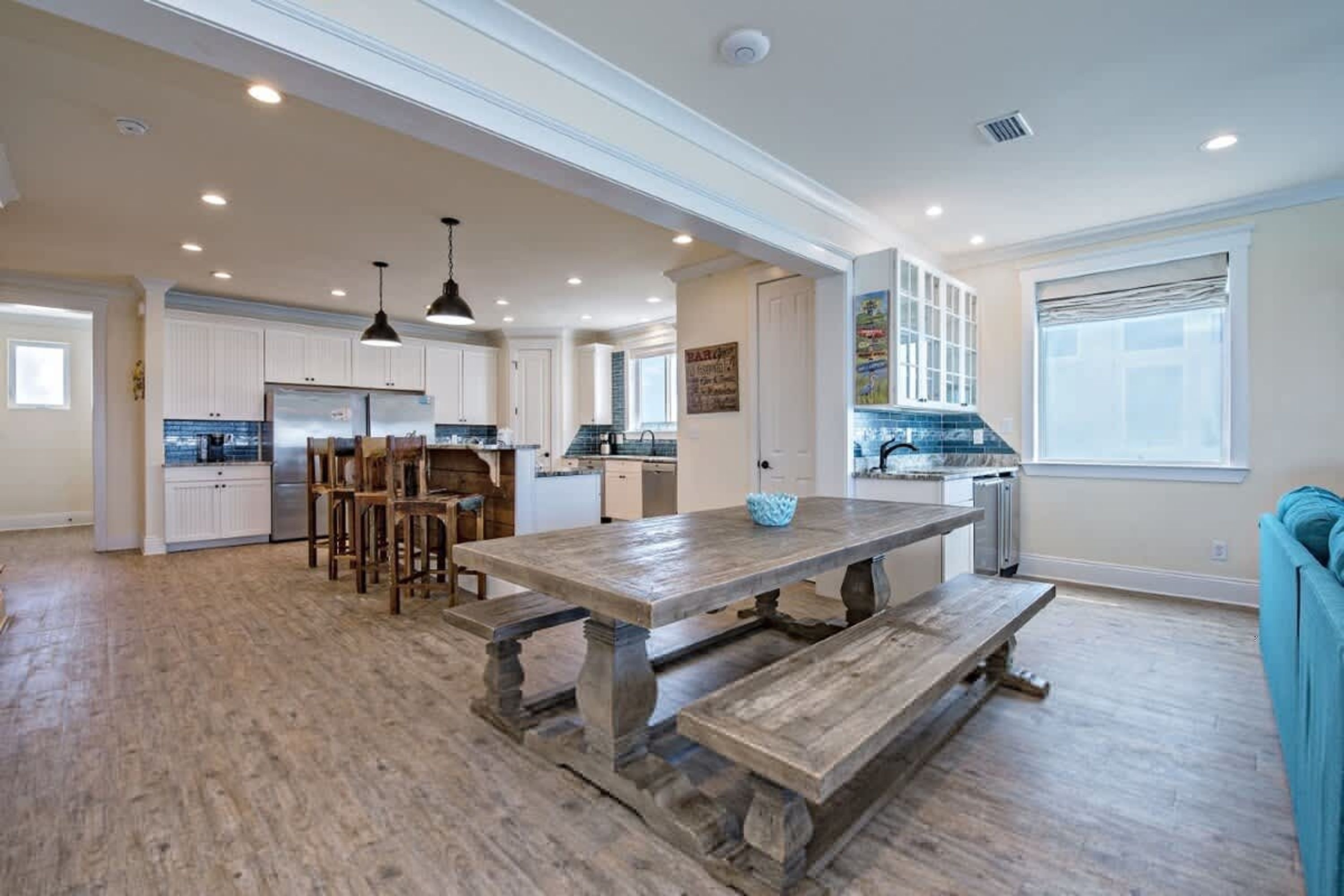 Una cocina amplia con una isla grande, suelo de madera e iluminación colgante.