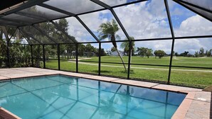 A rectangular pool with a clear blue water surface, surrounded by a brick border and a glass enclosure.
