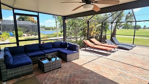 A covered patio with a sectional sofa, lounge chairs, and a coffee table.