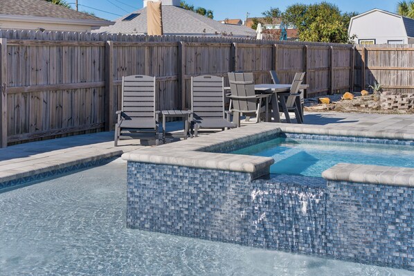 A swimming pool with a tiled edge, surrounded by a wooden fence, and outdoor furniture including chairs and a table. - House w/ Private Pool, Hot Tub and Basketball Court! Walking Distance to Beach! (Panama City Beach)