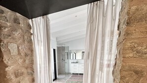 A stone-walled room with a view of a modern bathroom and a tiled floor.
