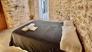 A stone-walled bedroom with a bed, pillows, and a small table.