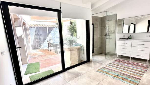A modern bathroom with a glass shower enclosure, a white vanity, and a large mirror.