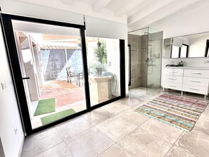Un baño moderno con cabina de ducha de vidrio, tocador blanco y un espejo grande.