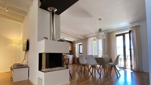 A modern living room with a fireplace, dining area, and kitchen in the background.
