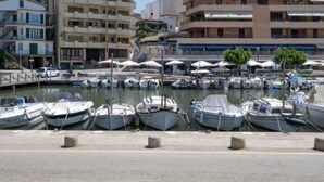 A marina with several boats docked, surrounded by multi-story buildings with balconies. - Villas2meet Casa Blanca Porto Cristo (Porto Cristo)