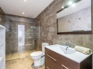 Un baño moderno con ducha, inodoro y tocador.