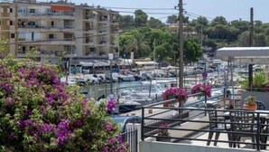 A marina with boats docked, surrounded by residential buildings and greenery. - Villas2meet Casa Blanca Porto Cristo (Porto Cristo)
