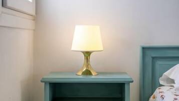 A teal bedside table with a gold lamp, a white wall, and a blue door.