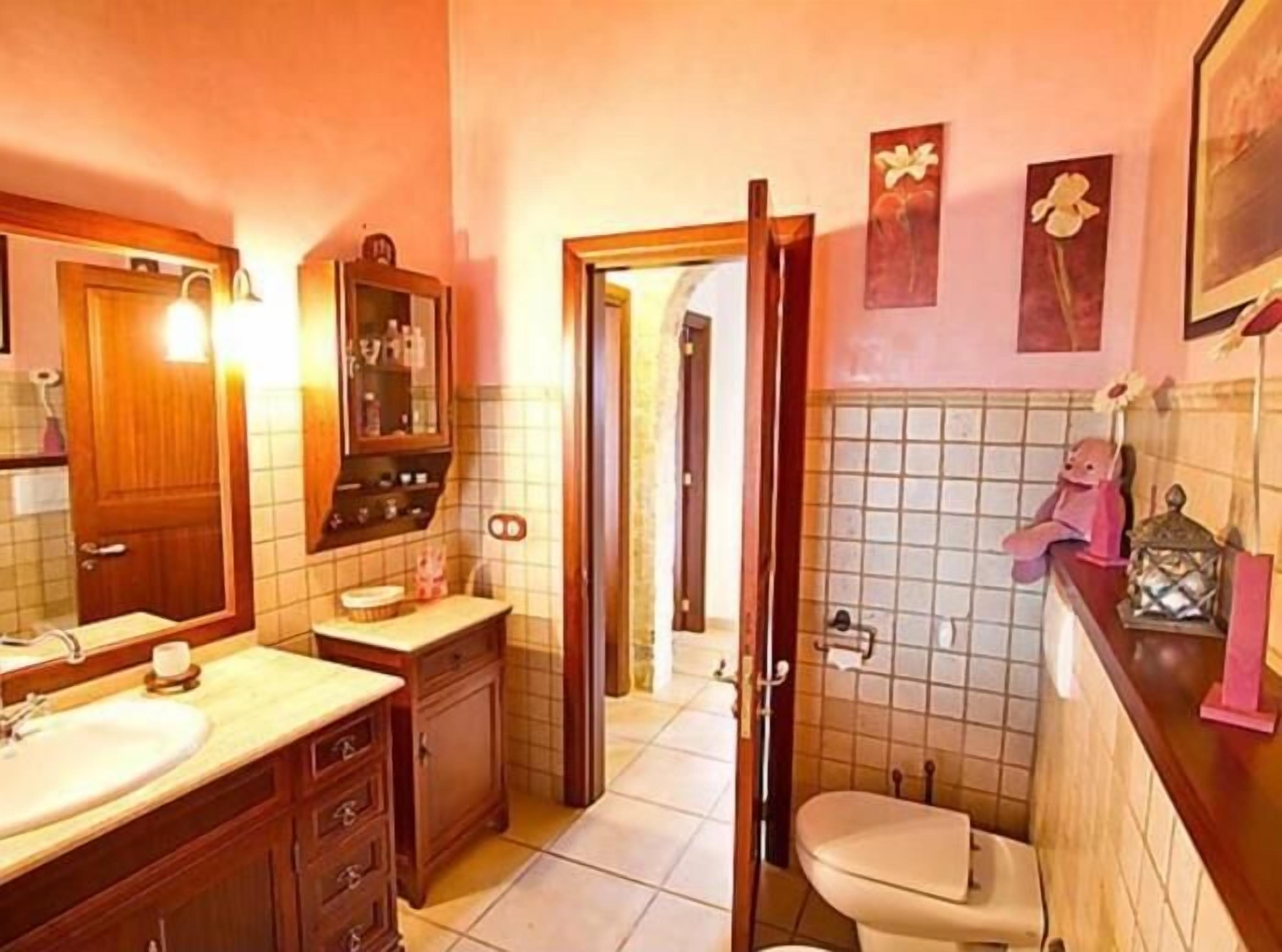 Ein Badezimmer mit Holzwaschtisch, Waschbecken, Spiegel, Toilette und Duschbereich.