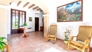 Una habitación amplia con zona de comedor, dos sillas de madera, un cuadro y suelo de baldosas.